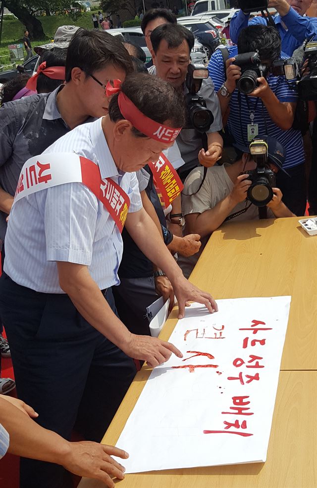 김항곤 성주군수가 13일 오전 사드성주배치 반대 범군민궐기대회에서 혈서를 쓰고 있다. 최홍국기자 hkchoi@hankookilbo.com