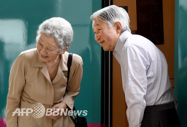 여름 휴가를 떠나는 아키히토 일왕(오른쪽)과 미치코 여사가 7월 25일 도쿄역에서 열차에 오르며 허리를 굽혀 인사하고 있다. AFP 뉴스1