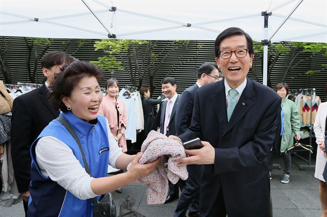 지난 4월 서울 여의도 산업은행 본점에서 사회공헌 기금 마련을 위해 열린 '사랑나누기 바자회'에서 이동걸(오른쪽) 산은회장이 참석자와 함께 바자회에 나온 물건을 들어 보이고 있다. 산업은행 제공