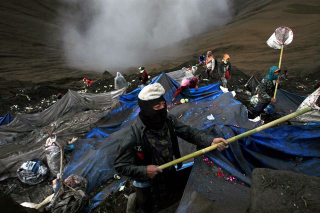 인도네시아 동부 자바 프로볼링고에서 21일(현지시간) 전통의 야드냐 카사다 축제가 열린 가운데 브로모 화산 분화구로 내려간 시민들이 그물망을 이용해 공물을 던지고 있다. 힌두 숭배자들은 풍요와 번영, 안녕을 위해 브로모 화산 분화구에 곡물, 과일,꽃,가축 등을 제물로 바친다. 신화 연합뉴스