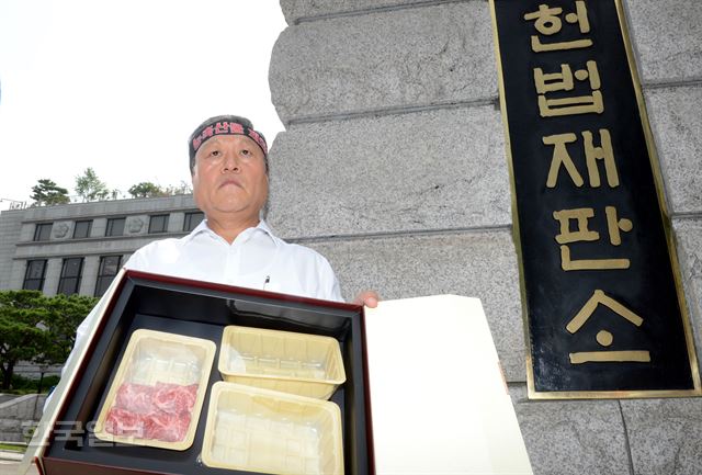 28일 ‘부정청탁 및 금품 등 수수의 금지에 관한 법률’(김영란법) 선고를 앞둔 서울 종로구 재동 헌법재판소 앞에서 한 농민이 한우 5만원어치를 들어 보이며 항의시위를 하고 있다. 신상순 선임기자ssshin@hankookilbo.com