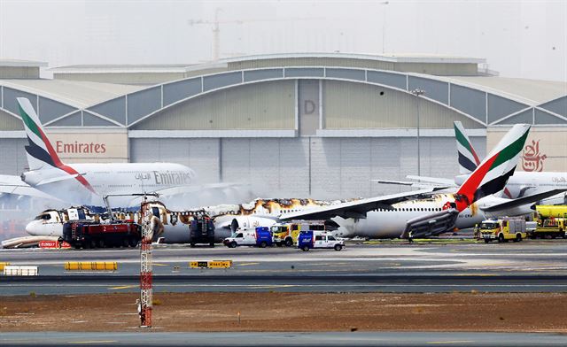 두바이국제공항 관계자들이 3일 랜딩기어 고장으로 비상 착륙한 에미레이트항공 보잉 777기를 점검하고 있다. 사고기는 비상착륙 때 발생한 화재와 폭발로 조종석에서 후미까지 동체 윗부분이 완전히 사라졌다. 두바이=EPA 연합뉴스