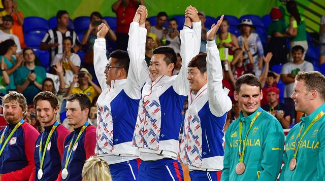 금메달을 차지한 한국 남자양궁 대표팀의 김우준(왼쪽부터), 구본찬, 이승윤이 7일 (한국시간) 브라질 리우데자네이루 마라카낭 삼보드로무 양궁장에서 열린 리우 올림픽 양궁 남자 단체전 시상식에서 양손을 높이 들고 환호하고 있다. 리우=올림픽사진공동취재단