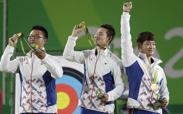 7일 브라질 리우데자네이루 삼보드로무 경기장에서 열린 리우올림픽 남자양궁 단체전에서 미국을 꺾고 금메달을 차지한 한국의 김우진(왼쪽부터), 구본찬, 이승윤이 시상대에 올라 금메달을 들어 보이고 있다. 리우데자네이루=AP 연합뉴스