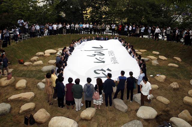 29일 오후 서울 남산공원 통감관저터에서 열린 '일본군 위안부 기억의 터 제막식'에서 더불어민주당 우상호 원내대표, 박원순 서울시장, 김복동 할머니와 길원옥 할머니를 비롯한 참가자들이 "기억하지 않는 역사는 되풀이된다"는 글귀가 4개 국어로 새겨진 '세상의 배꼽' 조형물의 가림막을 걷어내고 있다. 연합뉴스