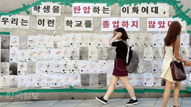 1일 2학기 개강을 맞은 이화여대 학생들이 서울 서대문구 본교 교정에서 미래라이프대학설립 반대 및 총장사퇴 등을 주장하는 '졸업장 반납' 게시물 앞을 지나고 있다. 배우한기자 bwh3140@hankookilbo.com