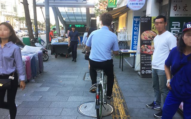 보행자 통행량이 많은 서울 중구 명동의 인도(人道)에서 한 시민이 자전거를 타고 이동하고 있다.