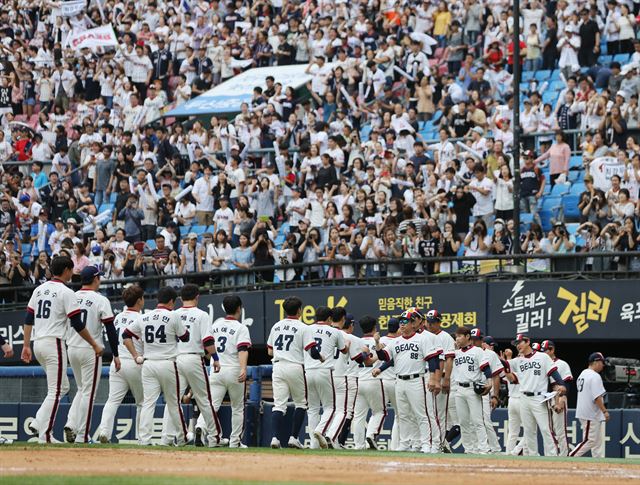 4일 잠실 삼성전에서 7-5로 승리한 두산 선수와 코칭 스태프들이 팬들을 앞에 두고 하이파이브를 하며 승리를 자축하고 있다. 연합뉴스