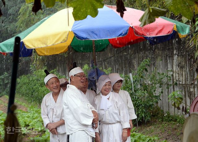 12일 오후 서울 노원구 마들체육공원에서 '마들농요와 함께하는 벼베기·탈곡 체험행사'에 참가한 마들농요보존회 회원들이 소낙비를 피하며 즐거워 하고 있다.배우한기자