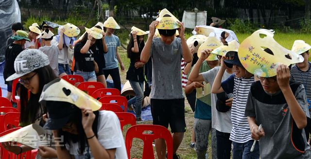 12일 오후 서울 노원구 마들체육공원에서 '마들농요와 함께하는 벼베기·탈곡 체험행사'에 참가한 초등학생들이 소낙비를 피하며 즐거워 하고 있다./배우한기자