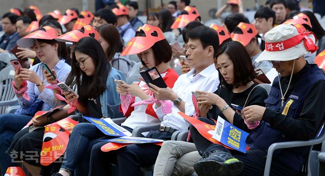 23일 오전 서울 마포구 성산동 월드컵 경기장에서 금융노조 조합원들이 성과연봉제에 반대하는 총파업 결의대회에 참석해 휴대폰으로 금융노조 파업 관련기사를 검색하고 있다.고영권기자youngkoh@hankookilbo.com