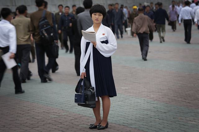 북한 평양에서 28일 이른 아침 출근 및 등교시간이 시작된 가운데 공책을 들고 공부를 하며 가던 한 여 학생이 잠시 멈춰 서 있다. 북한의 수도 평양은 여전히 세계 다른 나라 수도보다 매우 조용한 도시지만 매우 일찍 하루를 시작한다. AP 연합뉴스