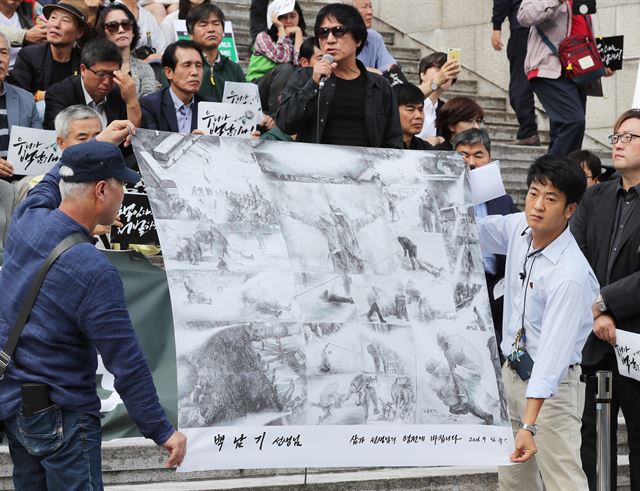 29일 오전 서울 종로구 세종문화회관 중앙계단에서 열린 '백남기 농민 사망 국가폭력 규탄 시국선언'에서 민중화가 임옥상(가운데)씨가 백씨가 물대포를 맞는 장면을 그린 '상선약수(최고의 선은 물과 같다)'를 펼쳐 보이고 있다. 연합뉴스