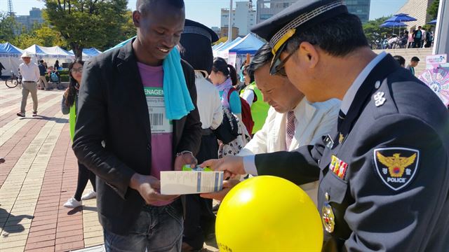 대전둔산서 임운택(오른쪽)ㆍ대전서부서 정규석(오른쪽 두번째) 외사계장이 9일 대전 둔산대공원에서 열린 ‘2016 다문화 화합한마당’에서 외국인에게 치안시책 등이 담긴 리플릿을 나눠주며 범죄 예방 및 법률 지원 등을 홍보하고 있다. 대전서부경찰서 제공.