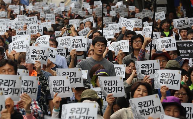 15일 오후 서울 종로구 영풍문고 앞에서 백남기투쟁본부가 개최한 범국민대회에서 참가자들이 '우리가 백남기다'라고 적힌 손피켓을 들고 부검영장 집행에 반대하는 구호를 외치고 있다. 연합뉴스