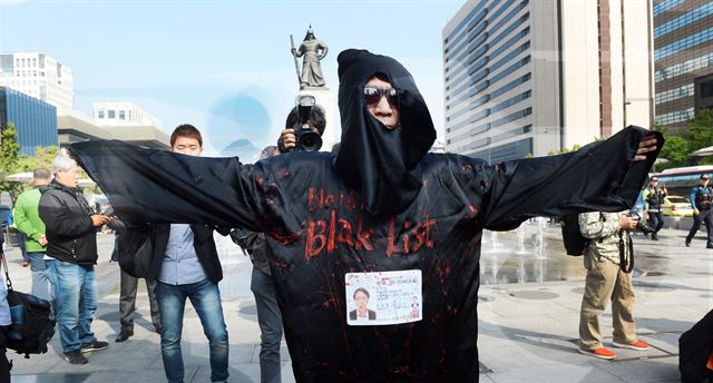 18일 오전 서울 광화문 광장 이순신장군 동상 앞에서 열린 '우리 모두가 블랙리스트 예술가다' 기자회견에 앞서 임옥상 작가가 청와대와 정부를 규탄 하는 퍼포먼스를 벌이고 있다. 신상순 선임기자ssshin@hankookilbo.com