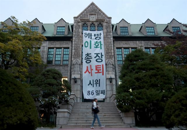 지난 21일 저녁 서울 서대문구 대현동 이화여대 본관 외벽의 시위 현수막 앞으로 한 학생이 지나가고 있다. 연합뉴스