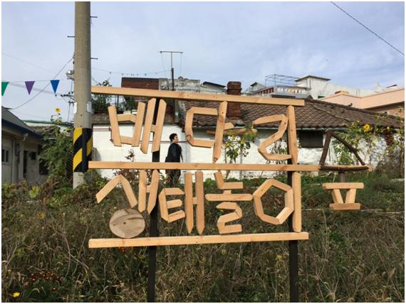 인천 동구 금창동 배다리마을을 관통하도록 계획된 산업도로 건설 예정지에 들어선 배다리 생태놀이 숲이 25일 문을 열었다. 27일 배다리 생태놀이 숲 나무 간판 뒤로 한 주민이 걸어가고 있다. 이환직 기자