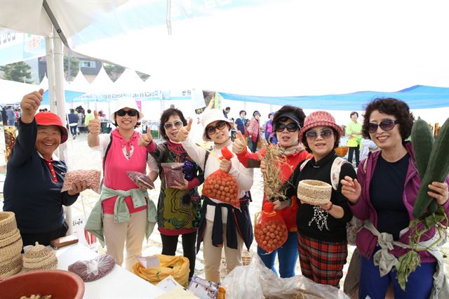 지난해 열린 무주 반딧불농특산물대축제장을 찾은 관광객들이 호두 등 특산품을 구입한 뒤 환하게 웃고 있다. 무주군 제공