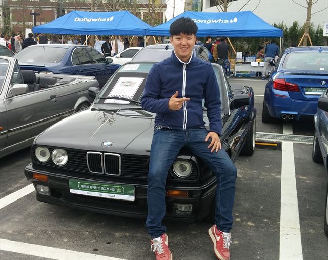 배민수씨가 자신의 명의로 된 생애 첫 차 92년식 BMW e30 320i 앞에서 포즈를 취하고 있다.