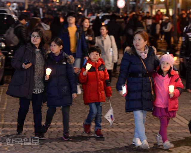 12일 저녁 서울 종로1가 거리에서 박근혜 대통령 퇴진을 요구하는 촛불집회에 참석한 가족들이 촛불을 들고 걷고 있다. 홍인기 기자 hongik@hankookilbo.com