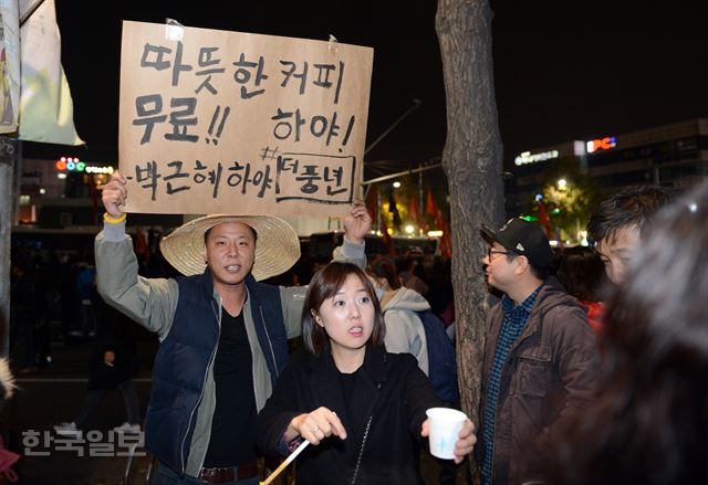 박근혜 하야 팻말을 든 남성과 한 여성이 12일밤 서울 경복궁역에서 시민들에게 무료 커피를 권하고 있다. 신상순 선임기자