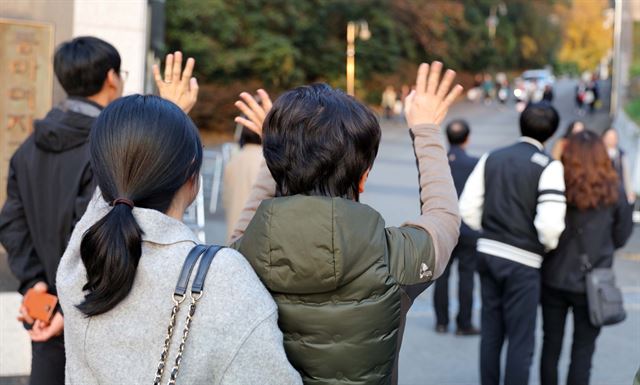 17일 오후 광주 남구 봉선동 동아여고 정문에서 학부모들이 대입수학능력시험을 치르고 나온 딸들을 기다리며 손을 흔들고 있다. 연합뉴스