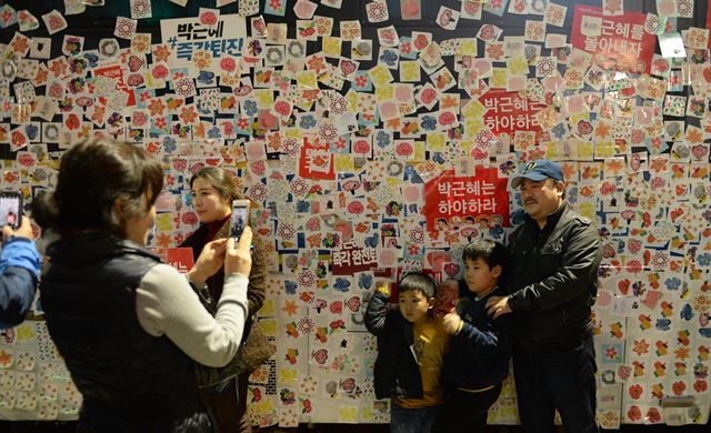 광화문광장에서 집회를 마친 시민들이 청와대로 향한 행진에서 경찰의 차벽에 막히자 시민들이 경찰차에 스티커를 붙이고 기념촬영을 하고 있다. /촛불을 켜든 아빠의 어깨에 오른 한 어린아이가 행진모습을 지켜보고 있다.오대근기자