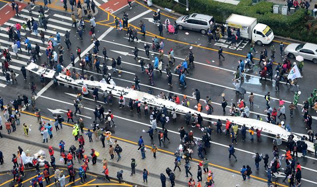 [161126-01] 26일 오후 서울 광화문사거리에서 민중미술가 임옥상이 500m 천 퍼포먼스를 진행하고 있다. 홍인기 기자 hongik@hankookilbo.com