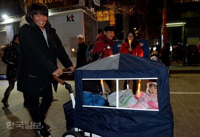 박근혜 대통령 퇴진 요구 대규모 촛불집회가 열린 26일 서울 광화문 광장에 한 시민이 아이들과 함께 참석하고 있다. 김주성기자 poem@hankookilbo.com