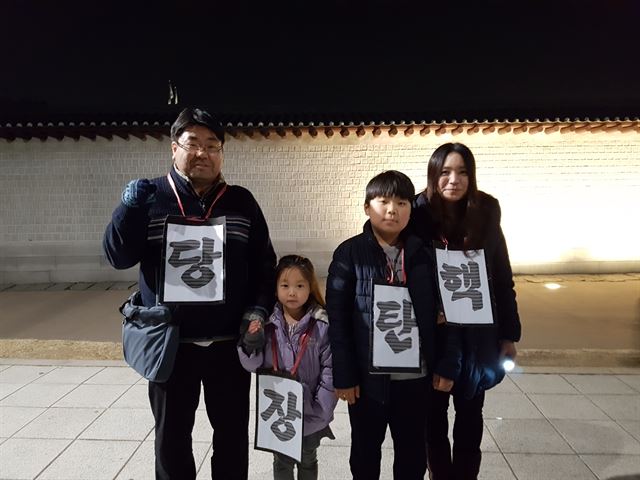 3일 서울 광화문광장에서 한 가족이 ‘당장 탄핵’ 구호가 쓰여진 팻말을 나눠 목에 걸었다. 김정현 기자