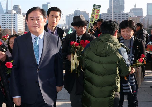 [투표 기권한 최경환 의원] 새누리당 최경환 의원(왼쪽)이 9일 오후 국회 본회의장에서 열린 박근혜 대통령의 탄핵소추안에 대한 표결을 위해 입장하다 환경운동연합 등 시민단체 회원들이 전달하는 '탄핵찬성 촉구' 꽃을 외면하고 있다. 반면 무소속 서영교 의원(오른쪽)은 웃으며 꽃을 받고 있다. 꽃에는 "촛불을 기억하세요". "탄핵에 찬성하세요"란 글귀가 붙어 있다. 이날 실시된 대통령 탄핵안 표결은 [찬성 234:반대 56]으로 가결되었다. 2016.12.9서울=연합뉴스