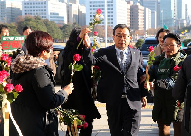 이정현 새누리당 대표가 9일 오후 서울 여의도 국회에서 열린 본회의에 참석하며 환경운동연합 등 시민단체들이 나눠주는 장미꽃을 뿌리치고 있다. 뉴스1