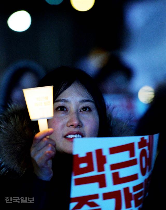 박근혜 대통령 탄핵안이 국회에서 가결된 9일 오후 서울 광화문광장에서 열린 촛불집회에 참석한 한 시민이 촛불을 들고 있다. 김주성 기자