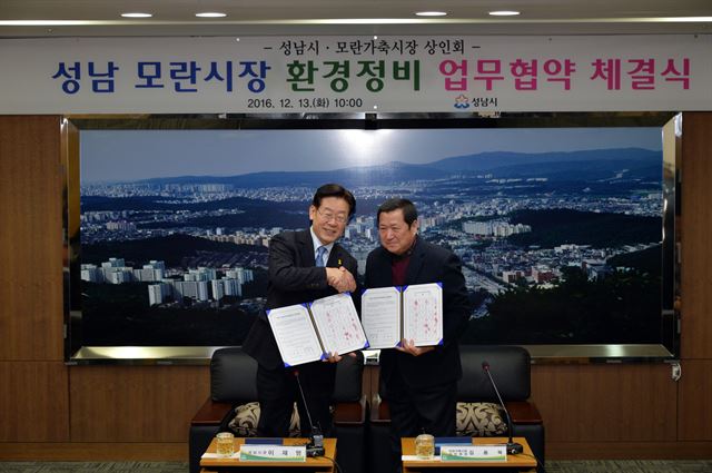 이재명(왼쪽) 성남시장과 김용복 모란가축시장 상인회장이 협약서에 서명한 뒤 악수하고 있다. 성남시 제공