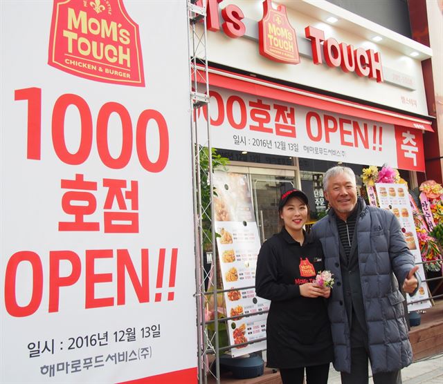 경기 수원 영통구에 문을 연 맘스터치 1,000호점 영통역점 앞에서 정리나(왼쪽) 점주와 정현식 해마로푸드서비스 대표이사가 기념 촬영을 하고 있다.