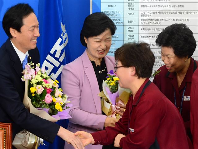 김영숙 국회환경미화원 노조 위원장과 조합원들이 16일 오전 서울 여의도 국회 더불어민주당 당대표실에서 열린 국회 청소용역 노동자 직접고용 타결 꽃 달기 행사에 참석해 추미애 대표와 우상호 원내대표에게 감사의 꽃다발을 전달하고 있다. 뉴시스