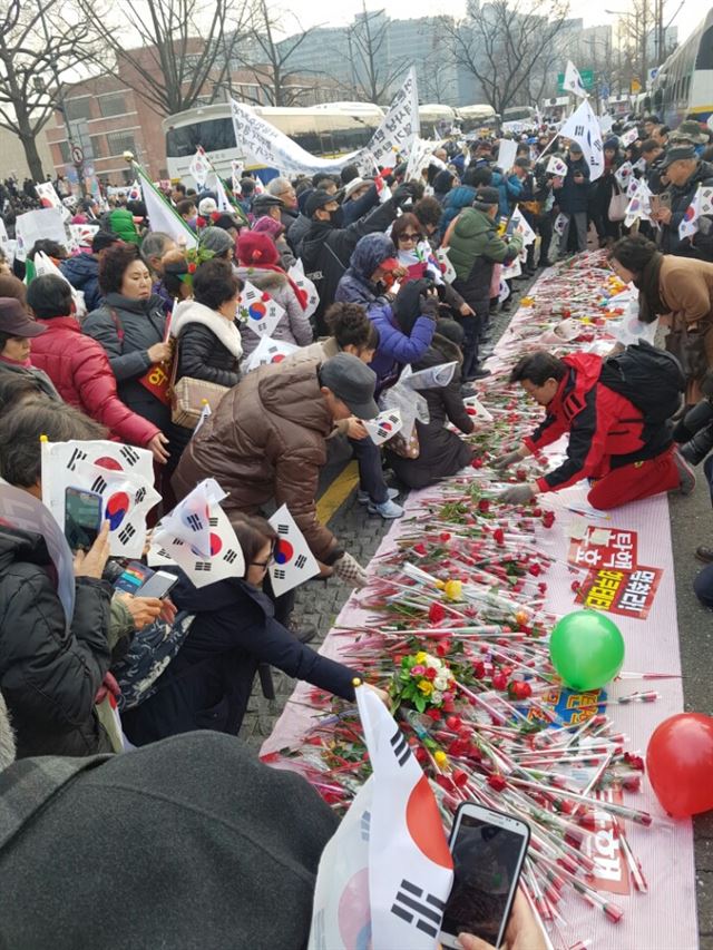 보수단체 회원들이 17일 서울 종로구 소격동 청와대 인근에서 박근혜 대통령을 지지한다는 의미로 빨간 장미꽃과 노란 종이비행기를 내려 놓고 있다. 정반석 기자