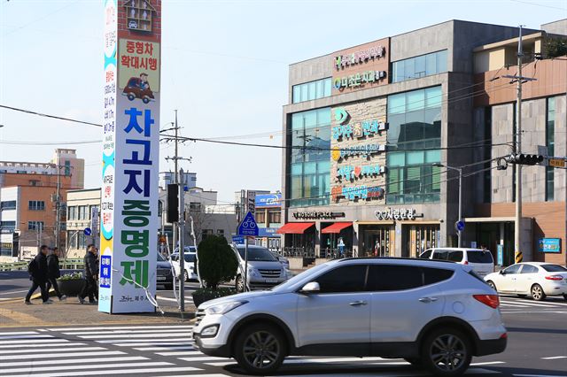 18일 제주시 8호 광장에 차고지 증명제 확대 시행 홍보물이 설치돼 있다. 제주시는 19개 동(洞) 지역의 대형차에 한해 시행되고 있는 차고지 증명제를 내년 1월 1일부터 중형차 이상으로 확대 실시한다. 연합뉴스