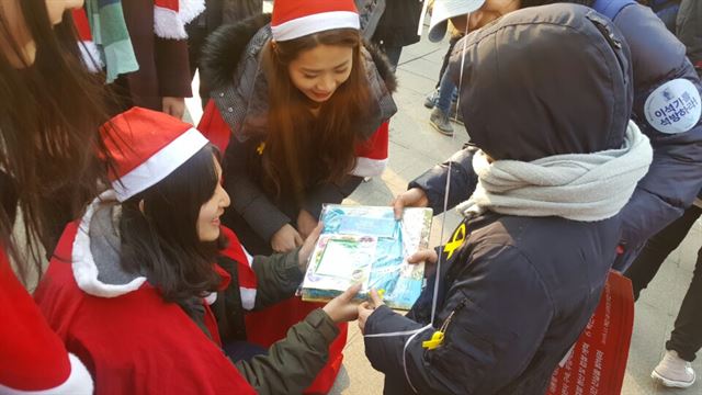 17일 서울 광화문광장에서 열린 박근혜퇴진청년산타대작전에 참석한 청년들이 아이들에게 선물을 나눠 주고 있다. 신지후 기자