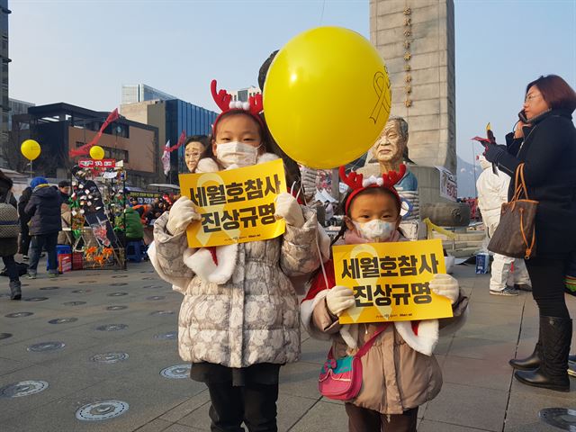 루돌프 머리띠와 함께 빨간색 망토를 두른 꼬마 산타들이 24일 오후 서울 광화문광장 이순신장군 동상 앞에서 세월호참사 진상 규명을 촉구하는 피켓을 들고 있다.