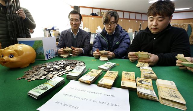 28일 오전 전북 전주시 덕진구 노송동 주민센터 직원들이 ‘얼굴 없는 천사’가 놓고 간 종이상자 안에 들어 있던 현금 다발과 동전을 세고 있다. 전주시 제공