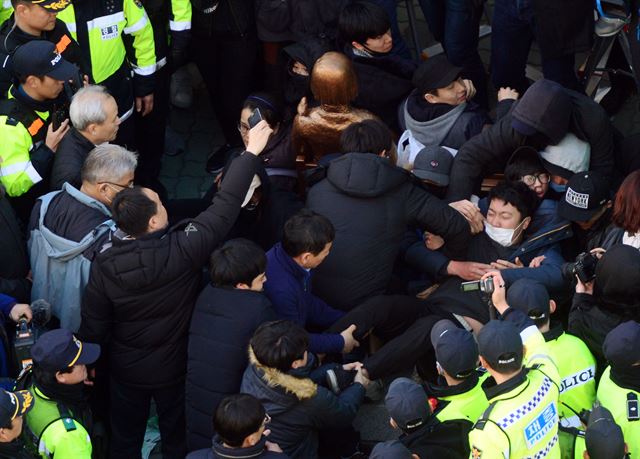 28일 오후 부산 동구 일본총영사관 앞에 부산시민단체가 기습적으로 평화의 소녀상을 설치한 이후 철거를 막기 위해 연좌농성을 벌이고 있는 가운데 동구청 직원들이 농성 중인 대학생들을 끌어내고 있다. 뉴시스