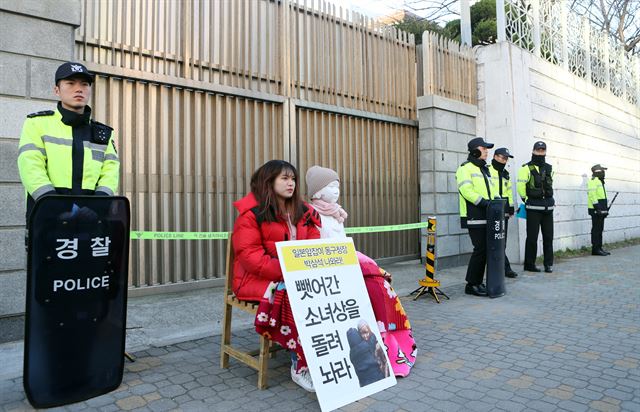 부산 동구청이 일본영사관 앞에 설치하려던 소녀상을 강제 압수한 가운데 29일 일본영사관 앞에서 한 시민이 소녀상 모형과 나란히 "소녀상을 돌려내라"는 피켓을 들고 1인 시위를 벌이고 있다. 연합뉴스