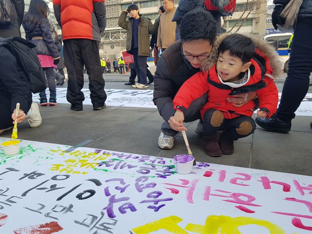 31일 오후 광화문미술행동이 서울 광화문광장에 설치한 대형 천에 시민들이 새해 맞이 문구를 쓰고 있다. 김정현 기자