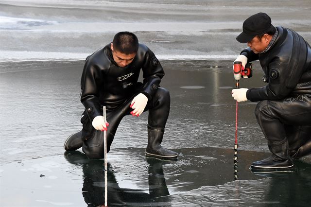 전문 잠수요원이 2일 산천어축제가 열릴 화천천의 얼음두께를 측정하고 있다. 화천군은 얼음두께가 10㎝에 그치자 축제 개막을 1주일 연기했다. 화천군 제공