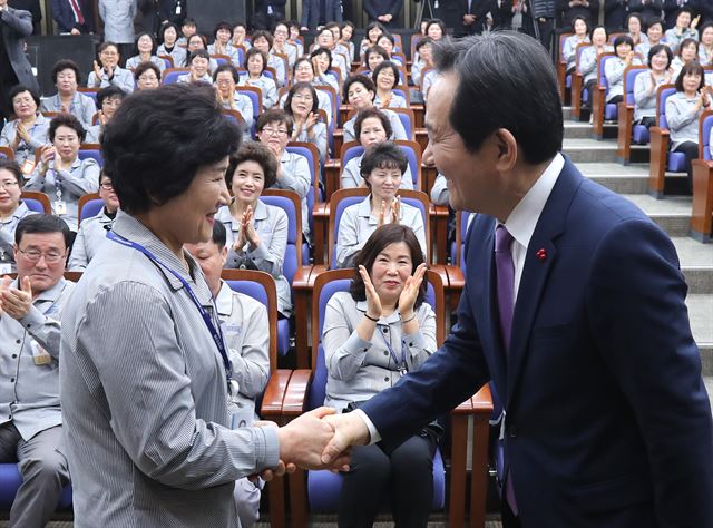 정세균 국회의장이 2일 오전 국회에서 열린 '국회 청소근로자' 직접고용 기념 신년행사에서 근로자 대표에게 국회 직원 신분증을 전달한 뒤 악수하고 있다. 비정규직 파견업체직원이었던 국회 환경미화원들은 정 의장이 취임한 뒤 직접 고용 의사를 밝혀 정부와의 관련 협의를 거쳐 이날부터 국회의 정식직원으로 일하게 됐다. 2017.1.2 연합뉴스