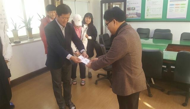 전남 순천시 연향중학교 학생회가 뇌출혈로 쓰러져 투병 중인 2학년 학우 이모(16)군의 치료비를 위해 모금한 성금 1,600여만원을 김종균 교감(왼쪽)이 이군의 아버지에게 전달하고 있다. 순천연향중 제공.