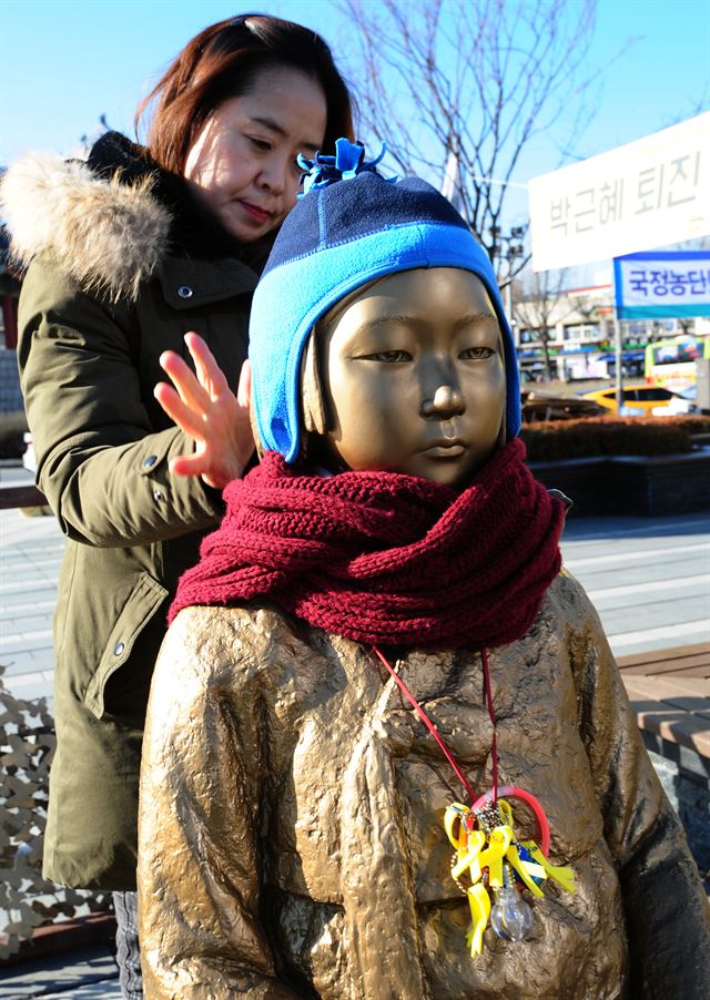 위안부 합의 1주년인 28일 전북 시민사회단체 관계자가 전북 전주시 풍남문광장에 설치된 평화의 소녀상에 목도리를 둘러주고 있다. 뉴스1