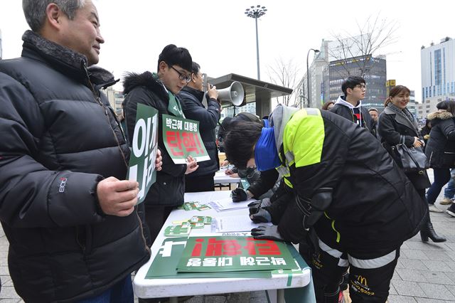 지난해 12월 7일 오후 서울 서대문구 신촌역 앞에서 열린 박근혜 대통령 퇴진 촉구 서명운동에서 패스트푸드점 아르바이트생들이 서명을 하고 있다. 뉴스1